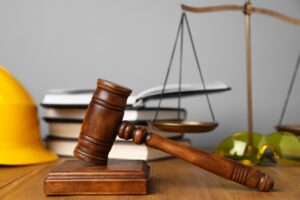 A judge's gavel, legal books, and a yellow safety helmet symbolizing the statutory framework of Florida workers' comp benefits.