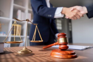 Rideshare accident lawyer shaking hands with a client over a desk with a gavel representing legal representation for Uber and Lyft accident victims in Port St. Lucie