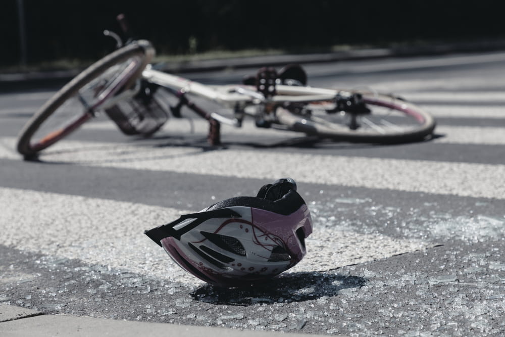 Cyclist helmet and broken glass on road after bicycle crash