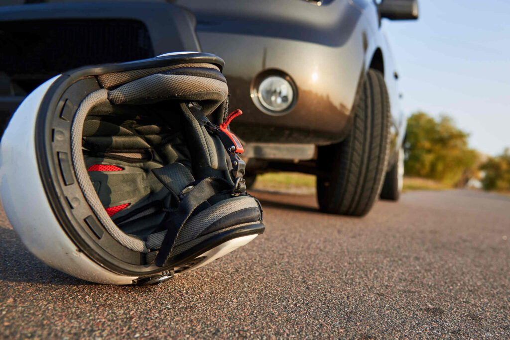 A white motorcycle helmet lying on the asphalt in front of a car after a collision on a West Palm Beach road.