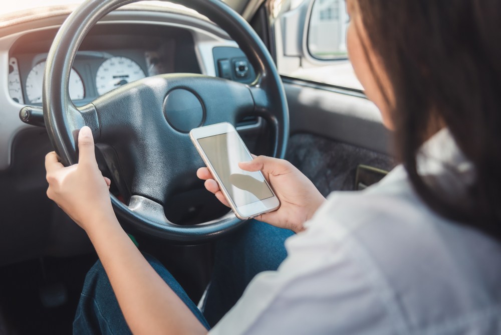 Female driver distracted by her phone while behind the wheel in Port St. Lucie representing negligent Uber driver behavior that leads to a rideshare accident claim
